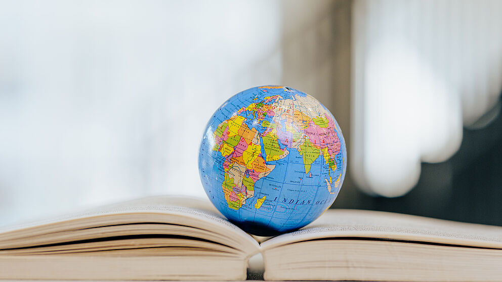 Ein Globus liegt auf einem aufgeschlagenen Buch