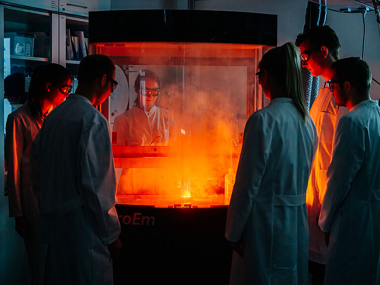 Chemie Studenten betrachten eine Reaktion im Abzug