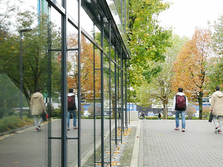 Two people are reflected in the glass front of the mensa at Paderborn University.